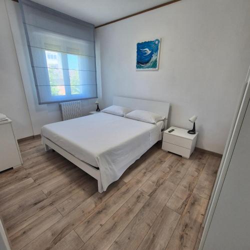 a white bedroom with a bed and a window at Appartamento Scossicci in Porto Recanati