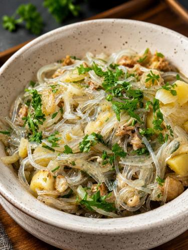 a bowl of noodles with parsley on a table at Lungta Homes in Bomdila