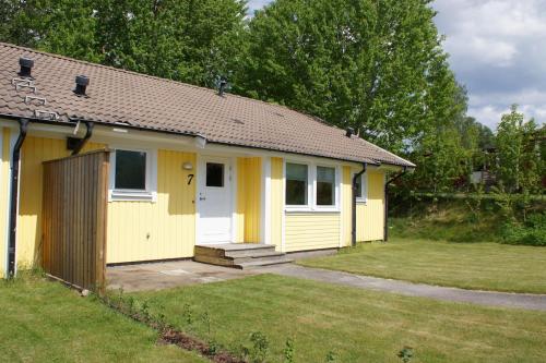 a yellow house with a white door in a yard at Gårdsjö 7 in Gårdsjö