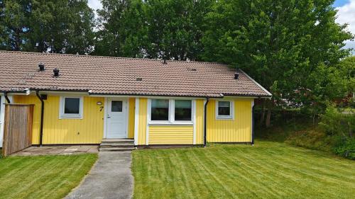 a small yellow house with a grass yard at Gårdsjö 7 in Gårdsjö