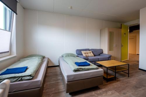 a room with two beds and a couch and a table at Work and Stay in Maasbree