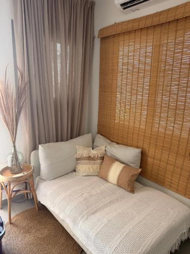 a couch with pillows sitting in front of a window at Palm Beach Vacay Suites - Garden Suite - Poolside in Palm-Eagle Beach