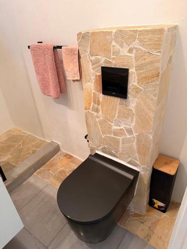 a bathroom with a black toilet in a stone wall at Palm Beach Vacay Suites - Garden Suite - Poolside in Palm-Eagle Beach