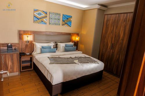 a bedroom with a large bed with blue pillows at Hotel La Falaise Bonapriso in Douala