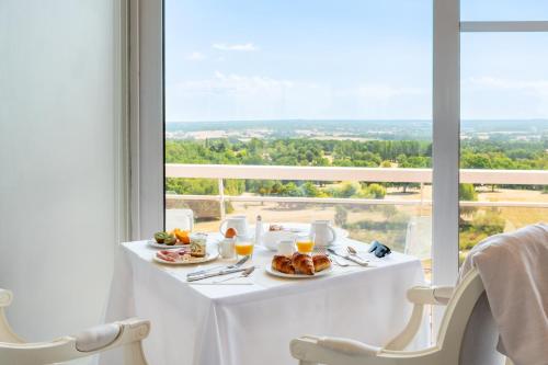 a table with plates of food and a large window at Domaine des Dryades - Hôtel & Spa in Pouligny-Notre-Dame
