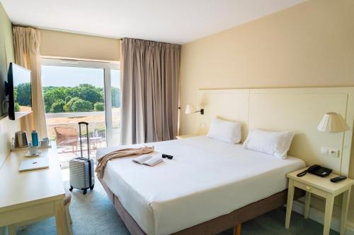 a hotel room with a large bed and a window at Domaine des Dryades - Hôtel & Spa in Pouligny-Notre-Dame