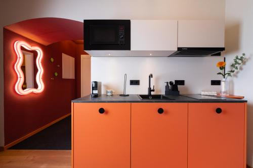 a kitchen with orange cabinets and a neon sign at stay micro Regensburg in Regensburg