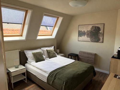 a bedroom with a bed and two windows at Harbour Stay Volendam in Volendam