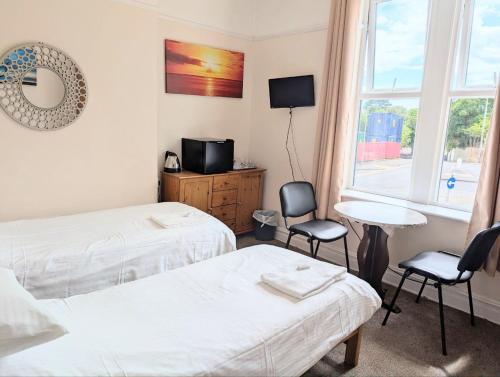 ein Schlafzimmer mit zwei Betten, zwei Stühlen und einem Fenster in der Unterkunft Dolphins Hotel in Bournemouth