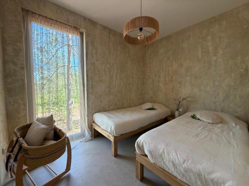 a bedroom with two beds and a chair and a window at Nest Spa Mirror Villas in Medemciems