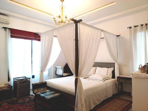 a bedroom with a canopy bed with a chandelier at Sainte Madeleine in Boumhel El Bassatine