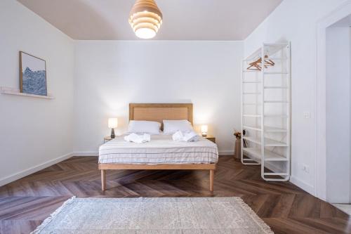 a white bedroom with a bed and a book shelf at BISCOTTAI Port Apartments in Trapani