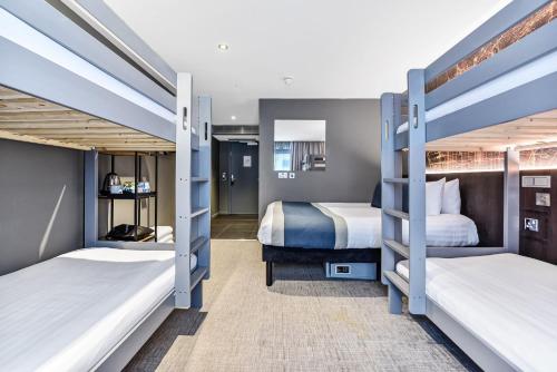 zwei Betten in einem Zimmer mit zwei Etagenbetten in der Unterkunft Heeton Concept Hotel – Luma Hammersmith in London