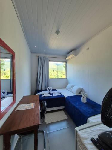 a room with two beds and a table and a desk at Pousada Refúgio Ouro Fino - Flats & Suítes in Paraty