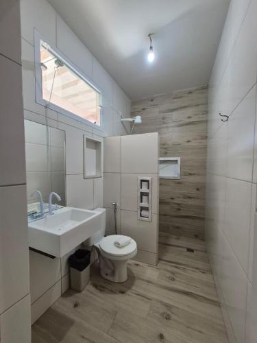 a white bathroom with a sink and a toilet at Pousada Refúgio Ouro Fino - Flats & Suítes in Paraty