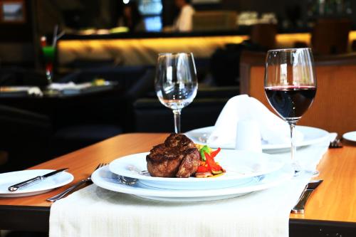 a table with a plate of food and two glasses of wine at Hotel Diego de Almagro Providencia in Santiago