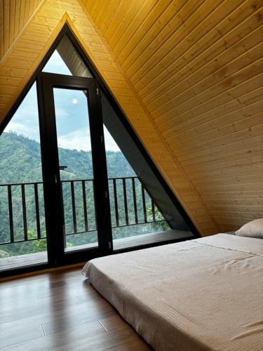 a bedroom with a bed and a large window at kesis chalet in Borjomi