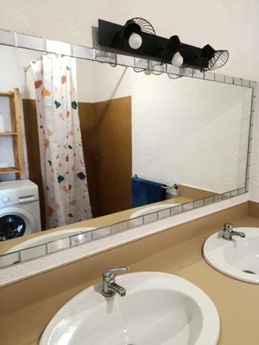 a bathroom with two sinks and a large mirror at Location appartement plain pied T3 à 8 KMS de l'océan in Lit-et-Mixe