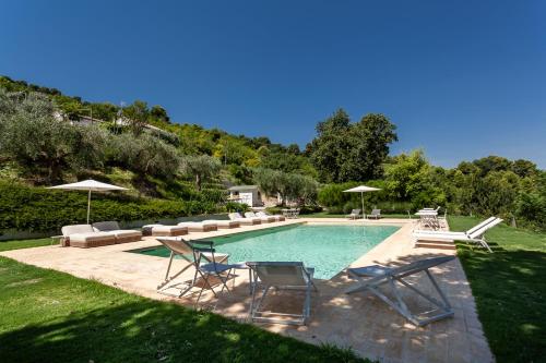 a swimming pool with chairs and umbrellas in a yard at Villa da Angelo by Mmega in Aquaviva Picena