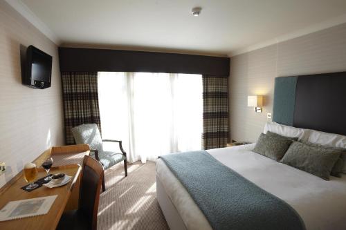 a hotel room with a bed and a desk and a bed and a chair at Best Western Plus Dunfermline Crossford Keavil House Hotel in Dunfermline