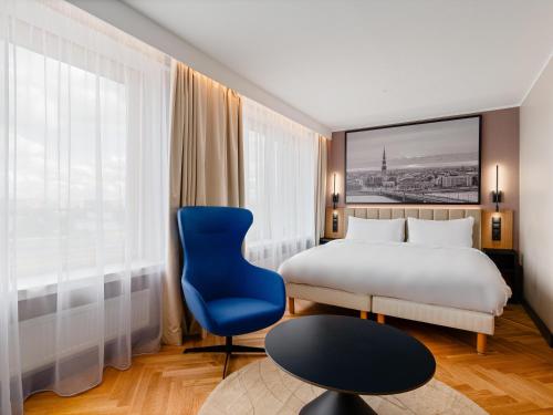a hotel room with a bed and a blue chair at Radisson Blu Hotel & Spa, Daugava Riga in Riga