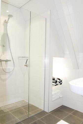 een witte badkamer met een glazen douchecabine en een wastafel bij Kodde Apartments in Aagtekerke