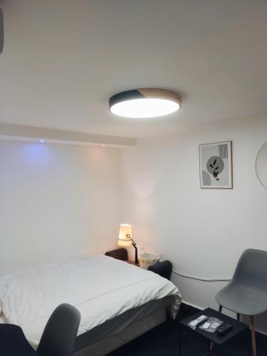 a bedroom with a bed and two chairs and a lamp at Chambre d'hôte à Wiltz in Wiltz
