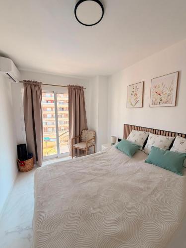 a white bedroom with a large bed and a window at Punta Prima Sun & Sea Apartament in Punta Prima
