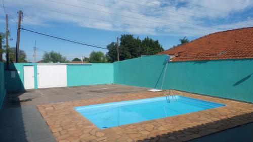 a swimming pool in front of a blue fence at Edícula Gigá in Brotas
