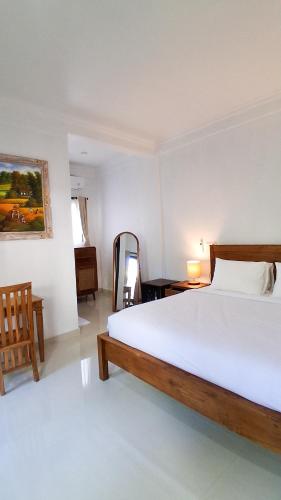 a bedroom with a large white bed and a chair at Rumah Merta Sari in Bingin Beach