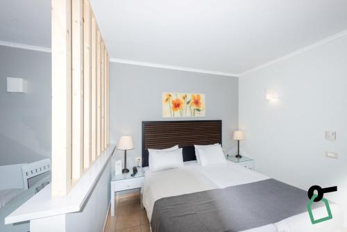 a white bedroom with a large bed and a window at Hotiday Corfu Kanoni in Corfu