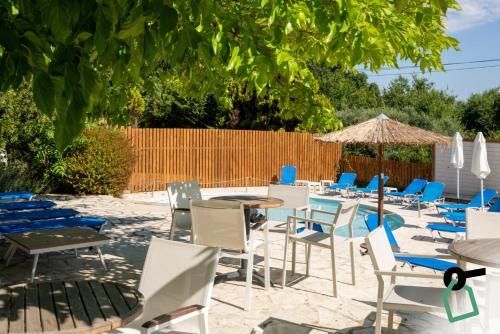 a patio with chairs and tables and an umbrella at Hotiday Corfu Kanoni in Corfu