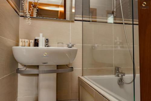 a bathroom with a sink and a mirror and a tub at Hotel La Falaise Bonapriso in Douala
