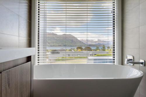 a white bath tub in a bathroom with a window at Grand Peninsula Lodge in Wanaka