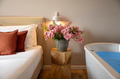 a vase of flowers on a table next to a bathtub at Rota Suites in Rota d'Imagna