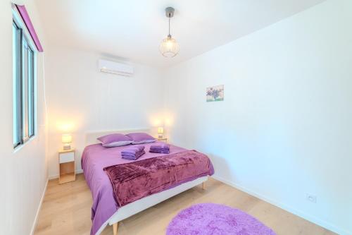 a bedroom with a bed with purple sheets and purple pillows at La Demeure des Sources - Iris - Avec climatisation in Bourbon-Lancy