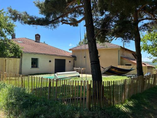 a house with a fence and a hammock in a yard at Gîte Alice Piscine privée in Hauterives