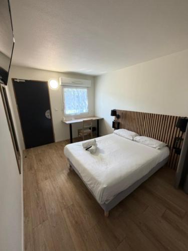 a bedroom with a bed and a desk and a window at Couett' Hotel Rumilly in Rumilly