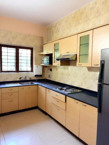 a large kitchen with wooden cabinets and a refrigerator at Siolim Serenity in Siolim