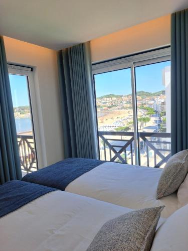 a bedroom with two beds and a large window at Beachfront 3bdr apt on Marginal Boulevard in São Martinho do Porto