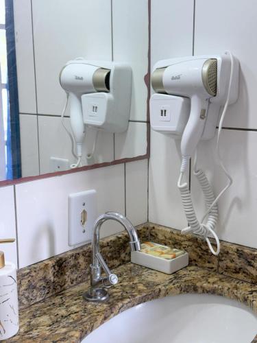 a bathroom sink with two hair dryers on a counter at Brothers Suites Centro Búzios in Búzios