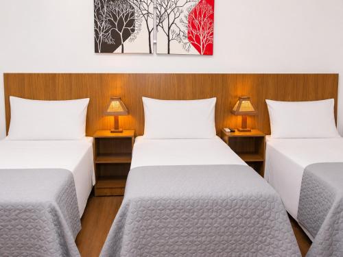 two beds in a room with two lamps at Ville de Montagne Hotel in Brumadinho