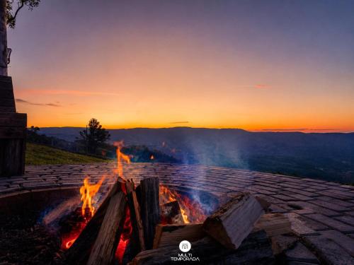 a fire pit with the sunset in the background at Rancho Sol Poente - Rancho Queimado - SC in Rancho Queimado