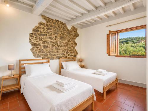 two beds in a room with a stone wall at Villa Le Balze Large Private Pool WiFi in Florence