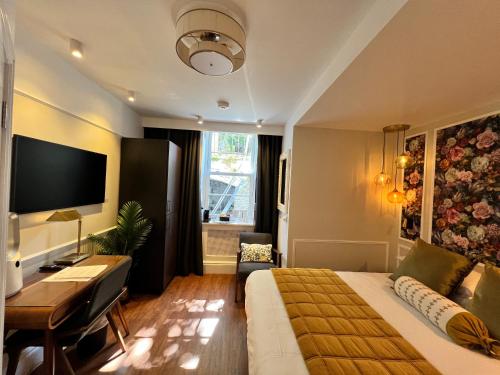 a hotel room with a bed and a desk and a television at Ferndale Mews in Bristol