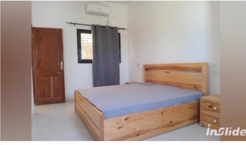 a bedroom with a wooden bed and a window at Perles de ngaparou in Saly Portudal