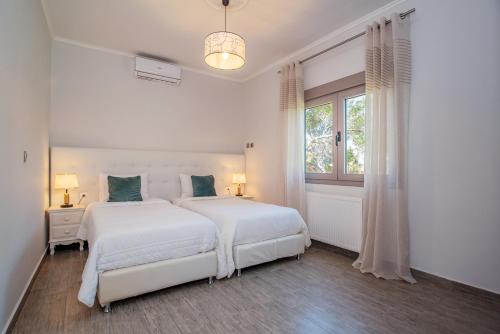 a white bedroom with two beds and a window at Villa giannis in Vitalades