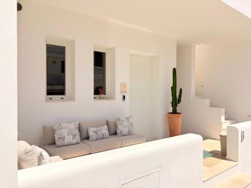 ein weißes Wohnzimmer mit Sofa und Kaktus in der Unterkunft Camere Assúd in Santa Maria di Leuca