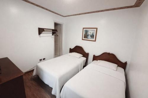 two beds in a room with white walls and wooden floors at Hotel Grer By Chat Noir in Cuenca