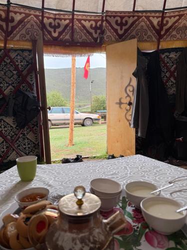 a table with bowls and plates on it with a view of a car at Yurt On The Mountain -With us you will feel the spirit of nomads in Svetlaya Polyana